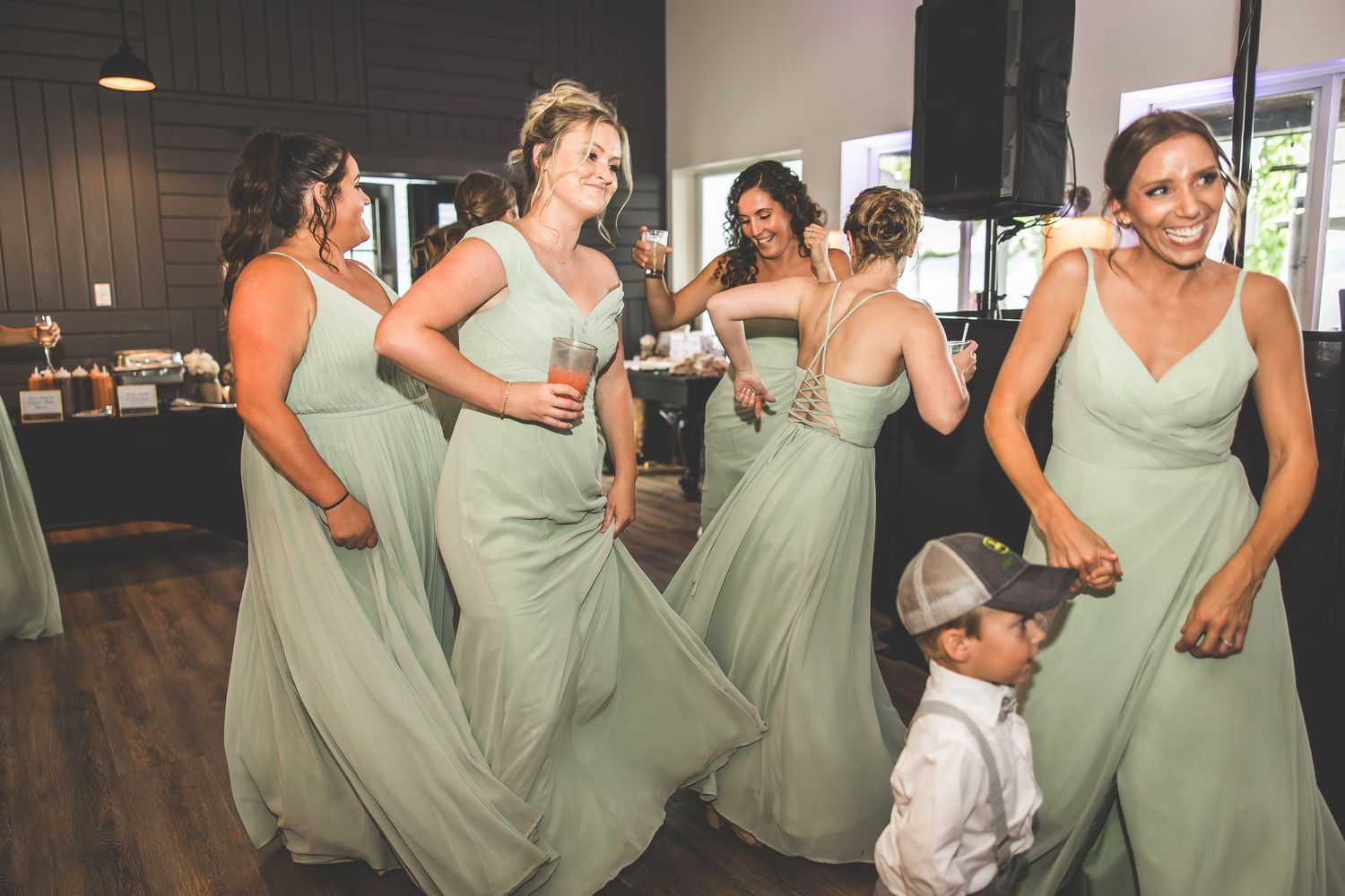 Bridesmaids in mint green dresses dancing together at a wedding reception.