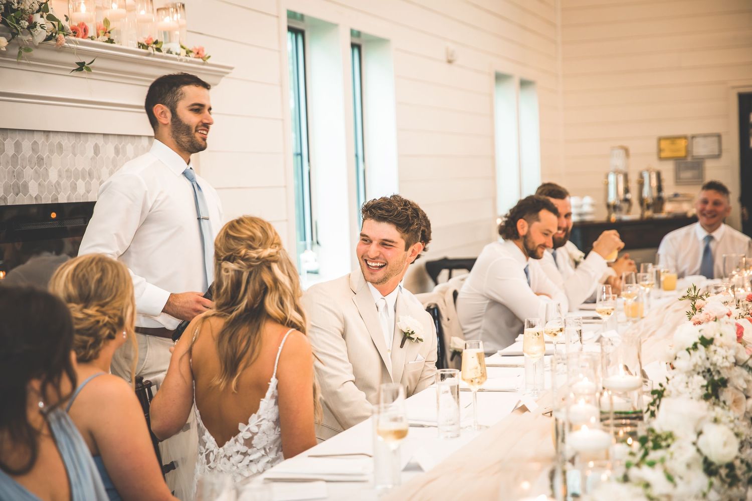 Wedding reception dining setup with elegant white table settings and floral centerpieces.