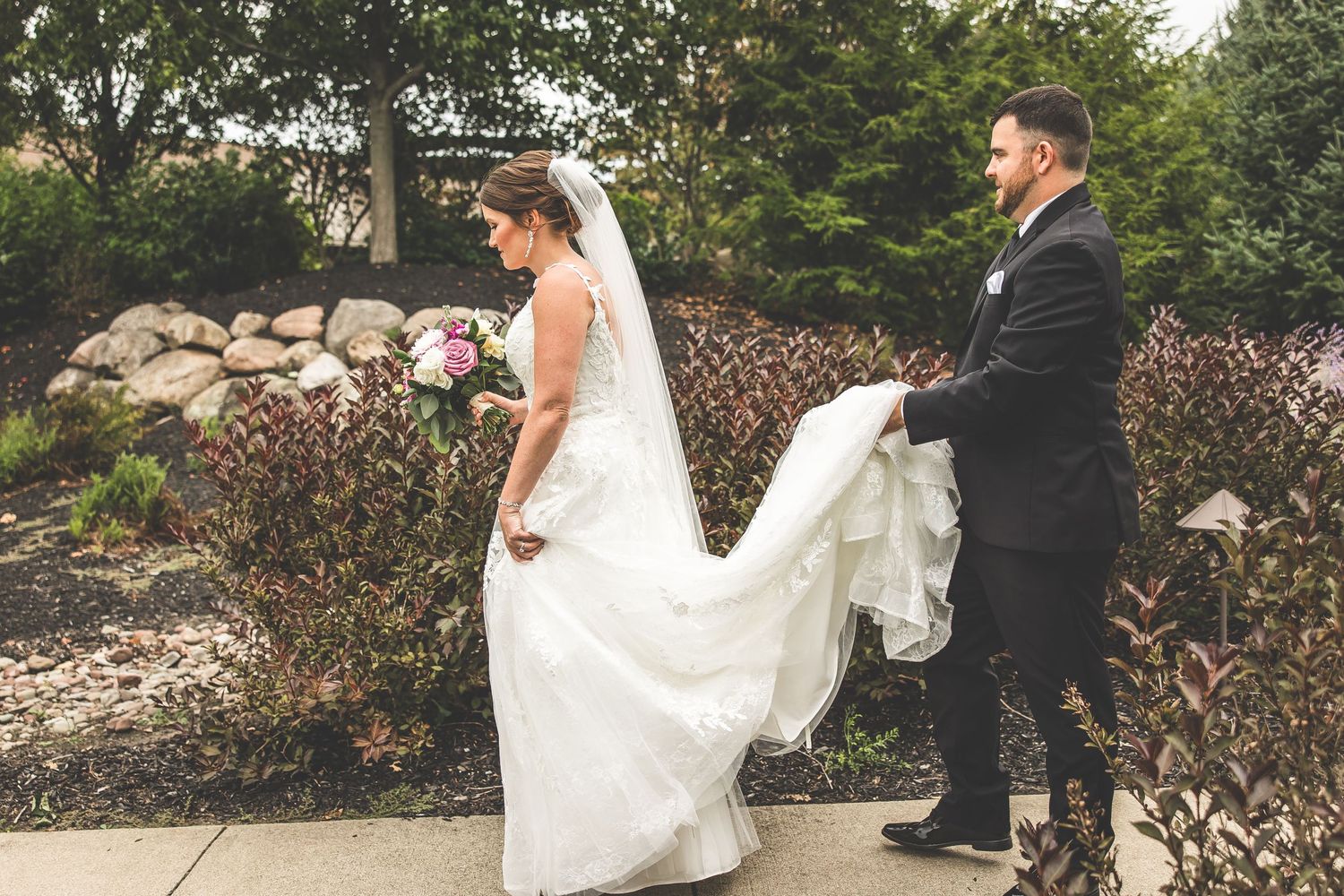 Bride and groom share a romantic moment in a lush outdoor garden setting.