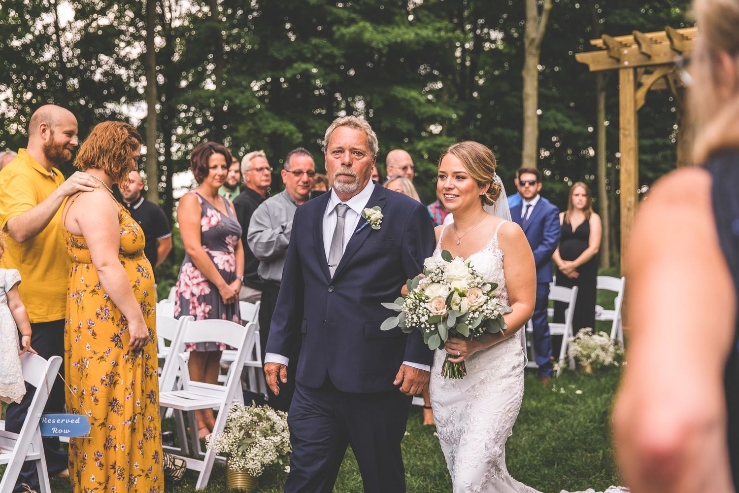 Wedding guests celebrating during outdoor ceremony among trees.