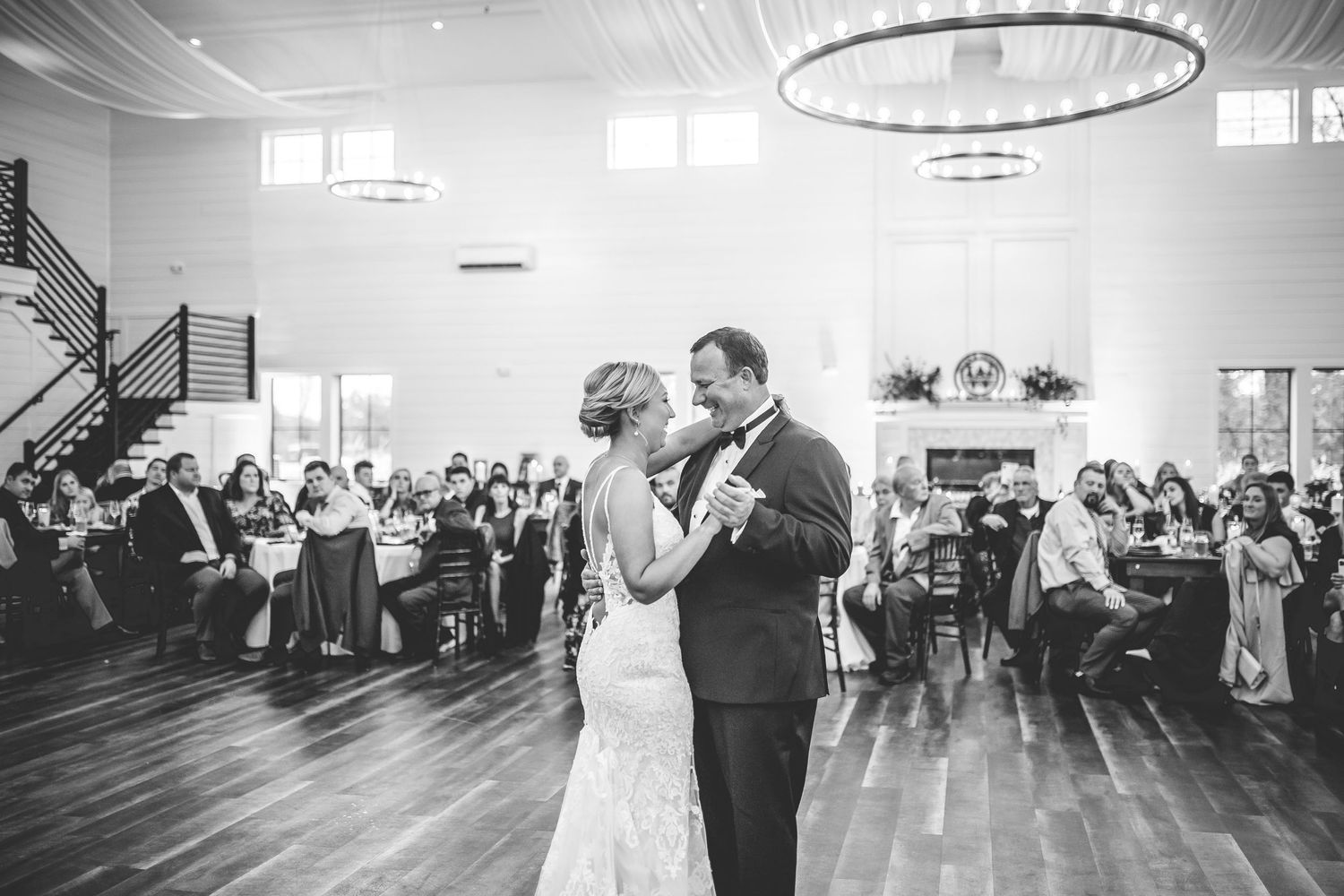 Wedding reception first dance sequence photographed in black and white with guests looking on.
