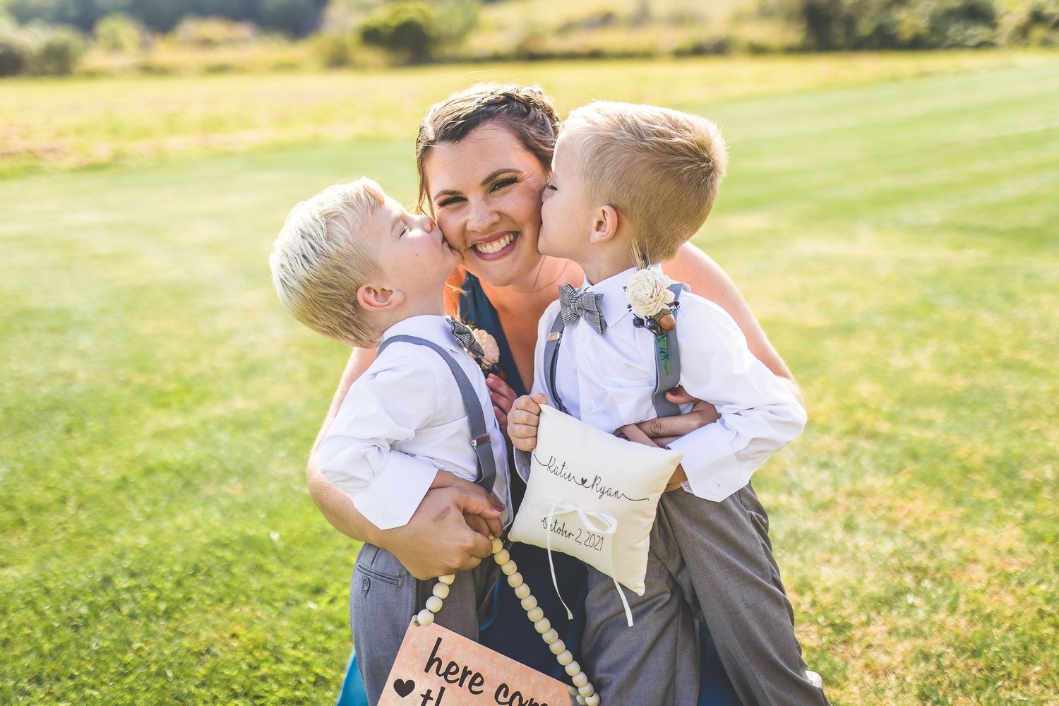 Sweet outdoor moment with ring bearer signs in a grassy field.