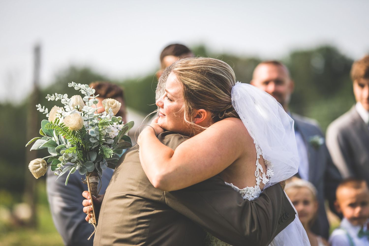 Emotional moments shared between wedding party members during outdoor celebration.