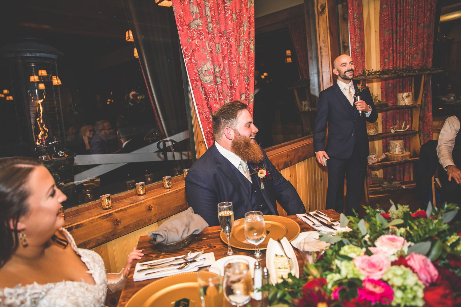Reception dinner tables feature elegant red and pink floral arrangements.