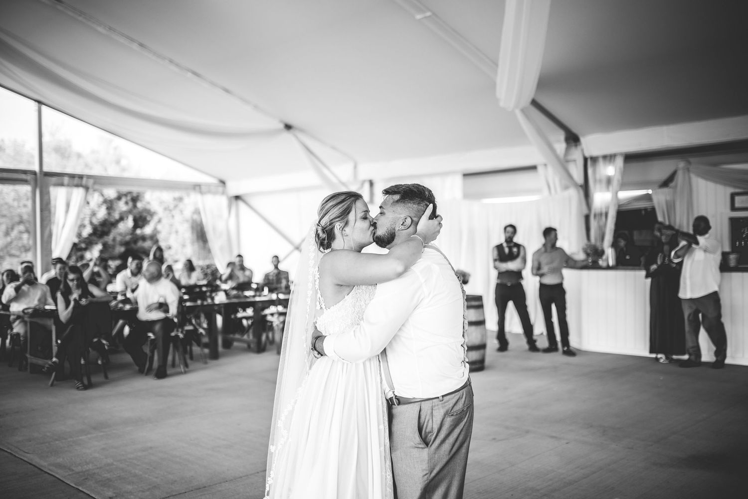 Black and white wedding reception photos showing joyful dancing moments under a tent.