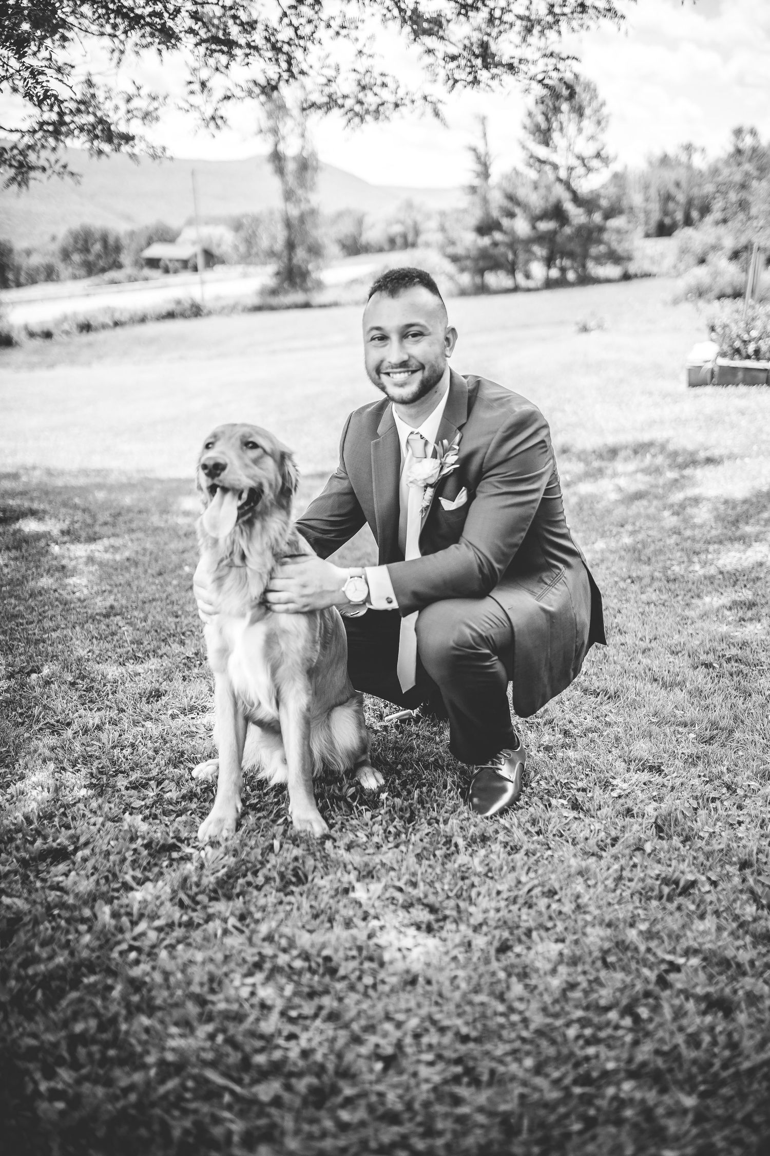 Black and white portraits with golden retriever dog and formal attire on grassy hill.