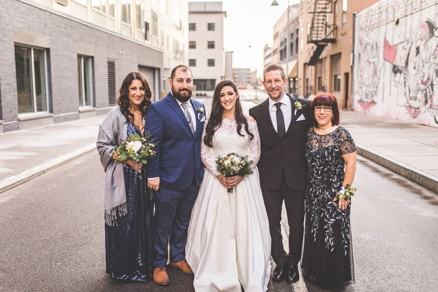 Wedding party members pose together on city street.