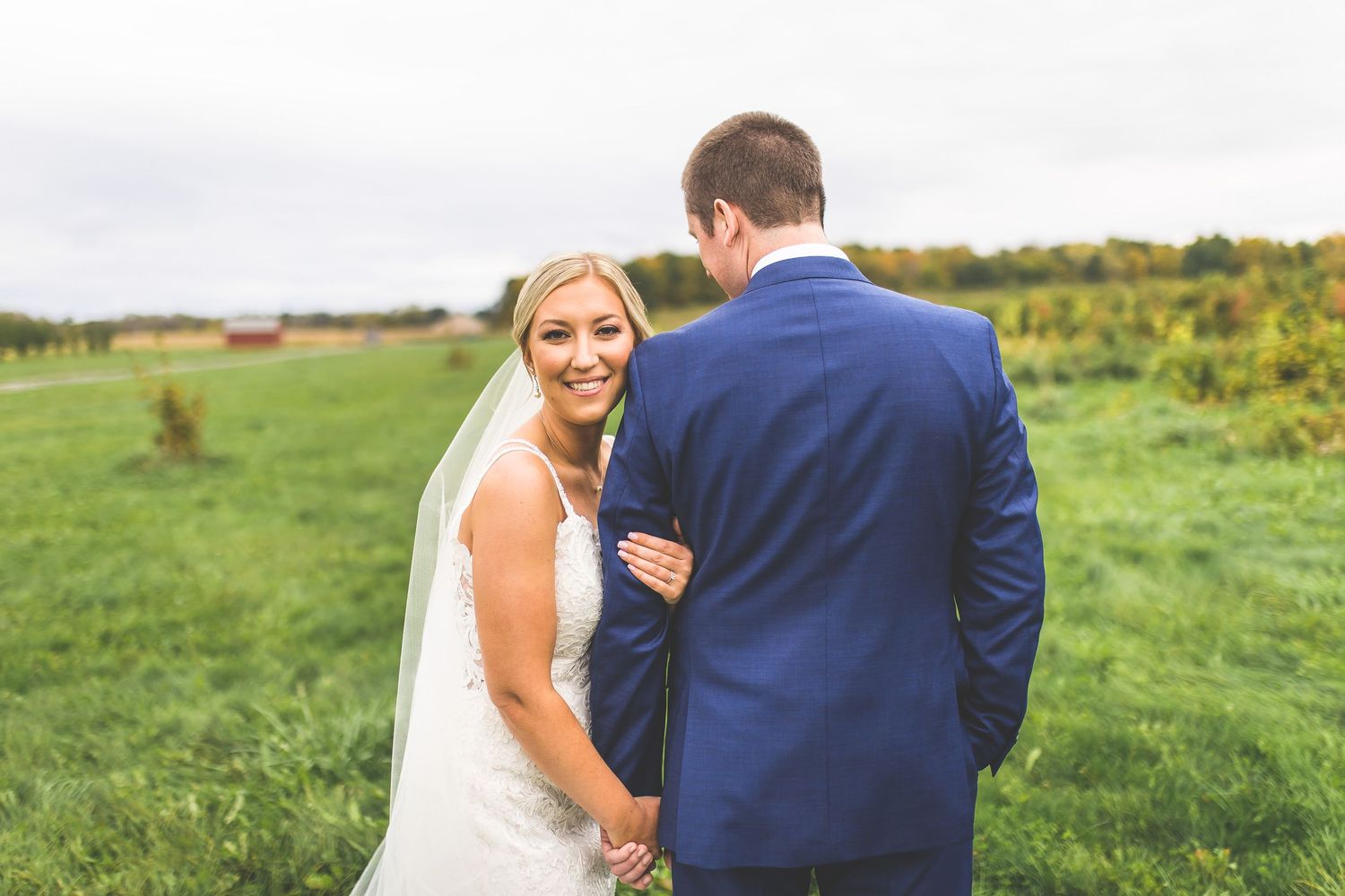 Candid wedding photos showing tender moments between newlyweds in a grassy field.