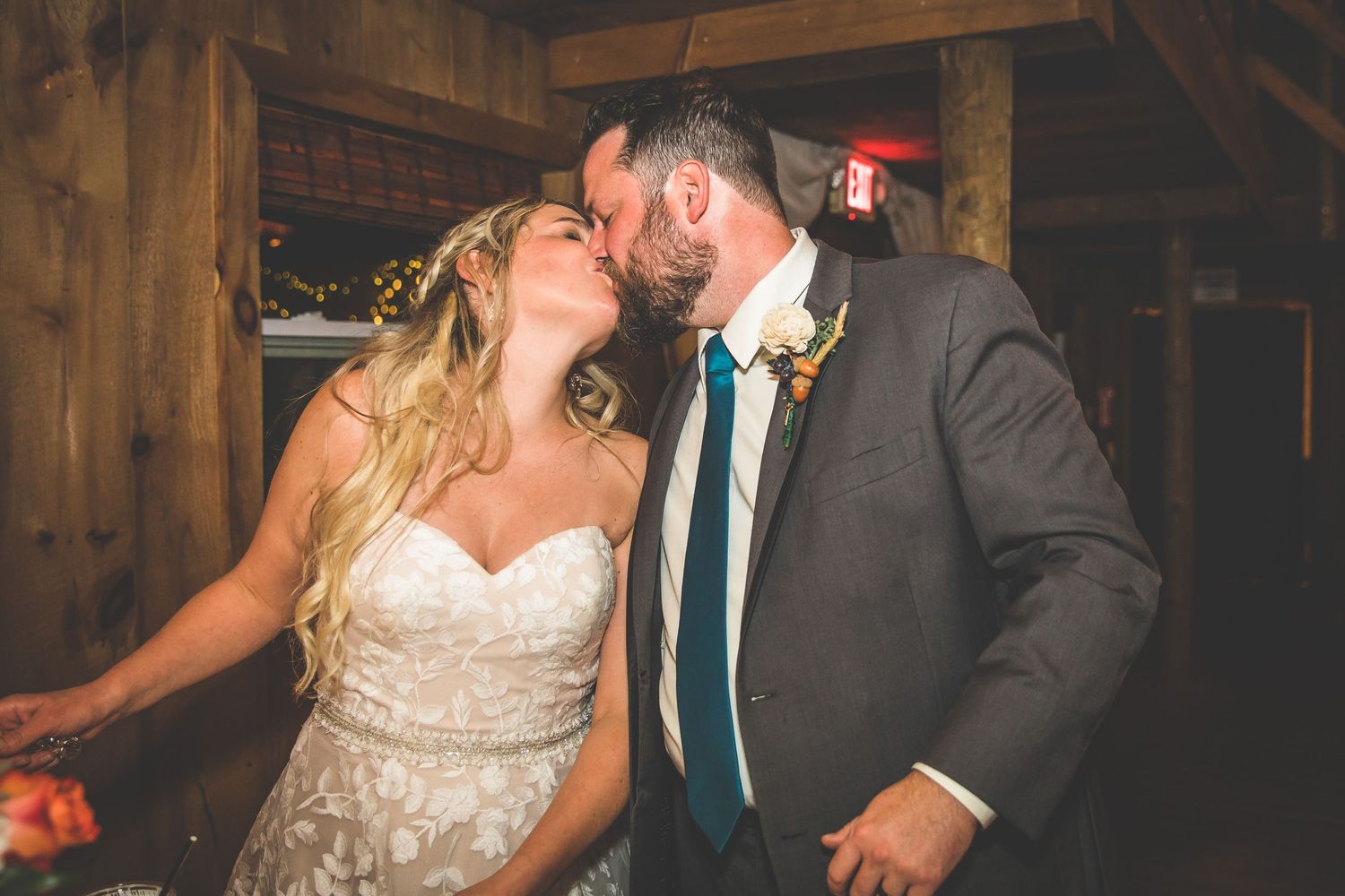 Couple dancing together at a rustic barn wedding reception with string lights overhead.