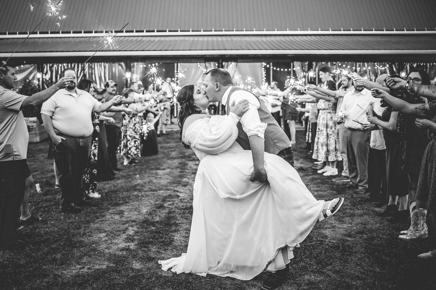 Black and white photo of wedding couple's dramatic sparkler exit finale.
