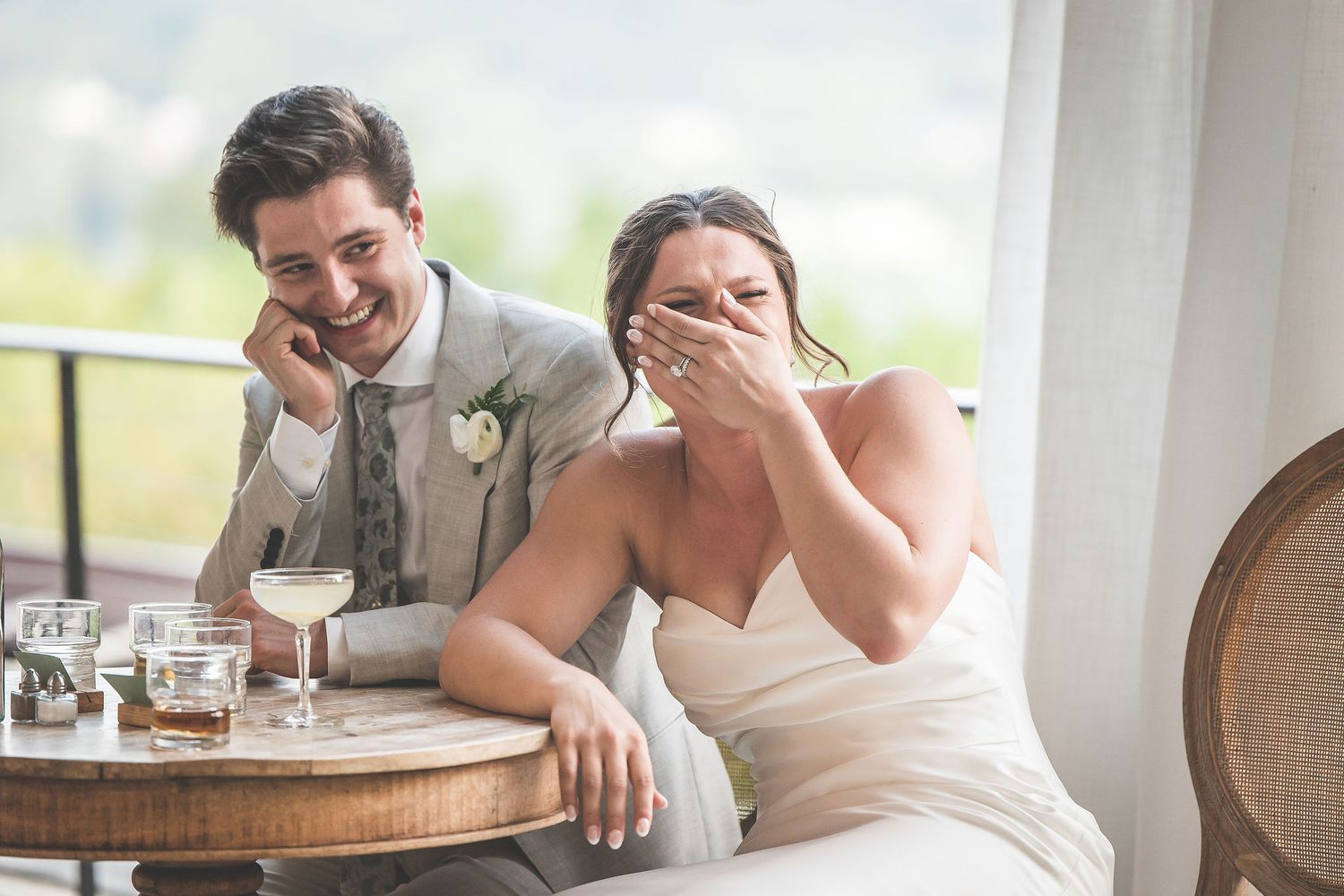 Candid moment of laughter shared between newlyweds at their reception table.