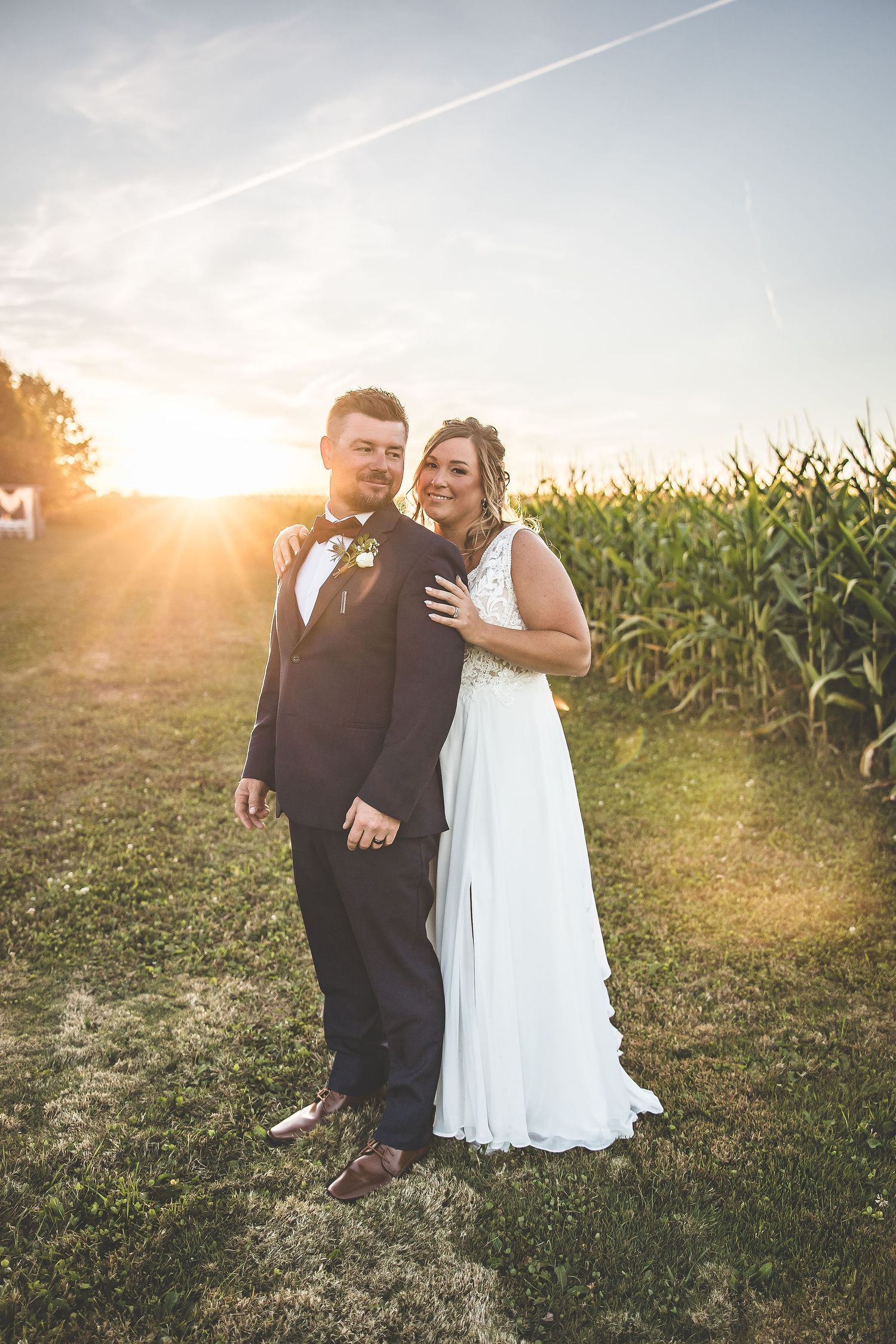Romantic sunset wedding photos taken near a cornfield with warm evening light.