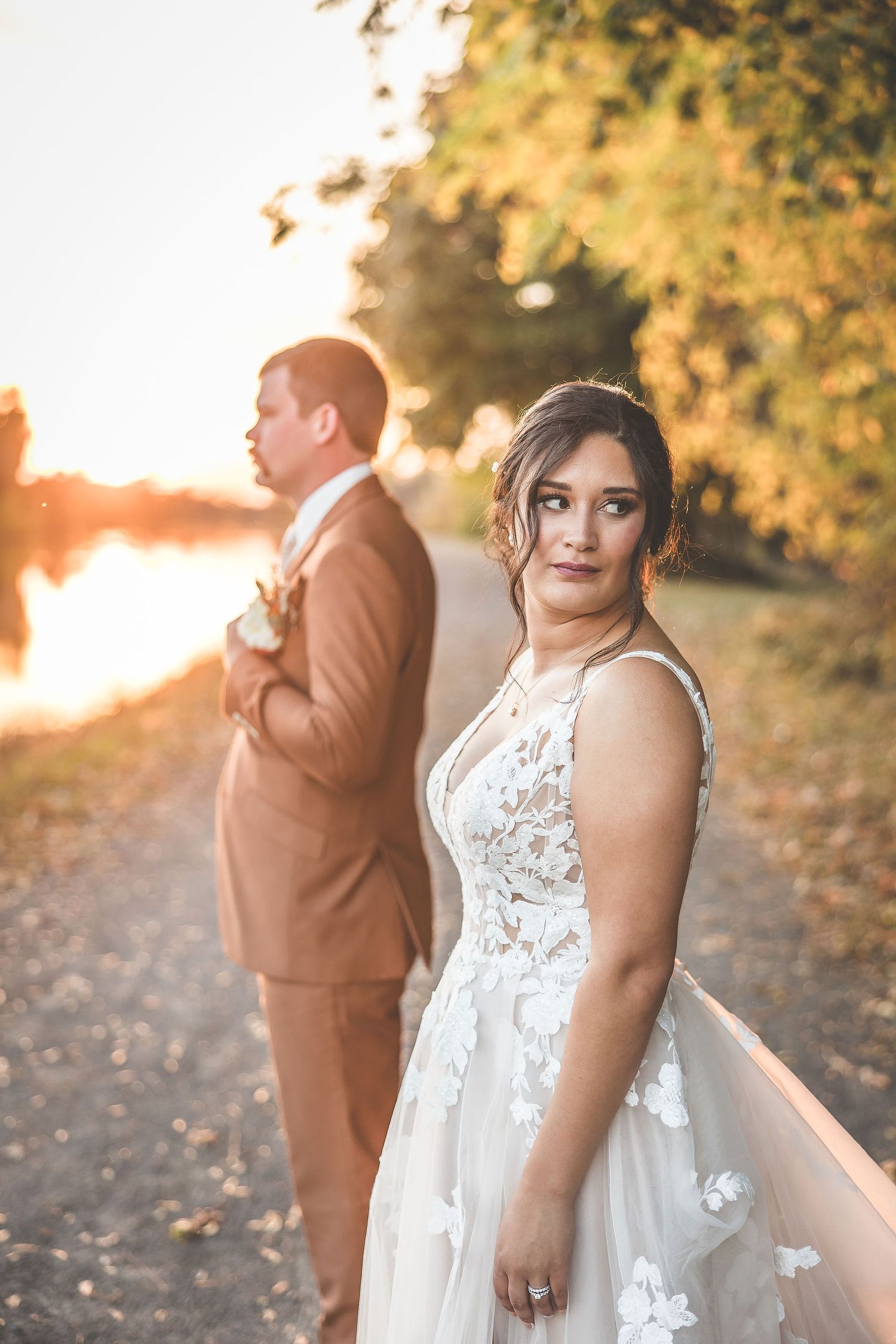 Romantic wedding portraits at sunset with soft golden lighting and natural scenery.