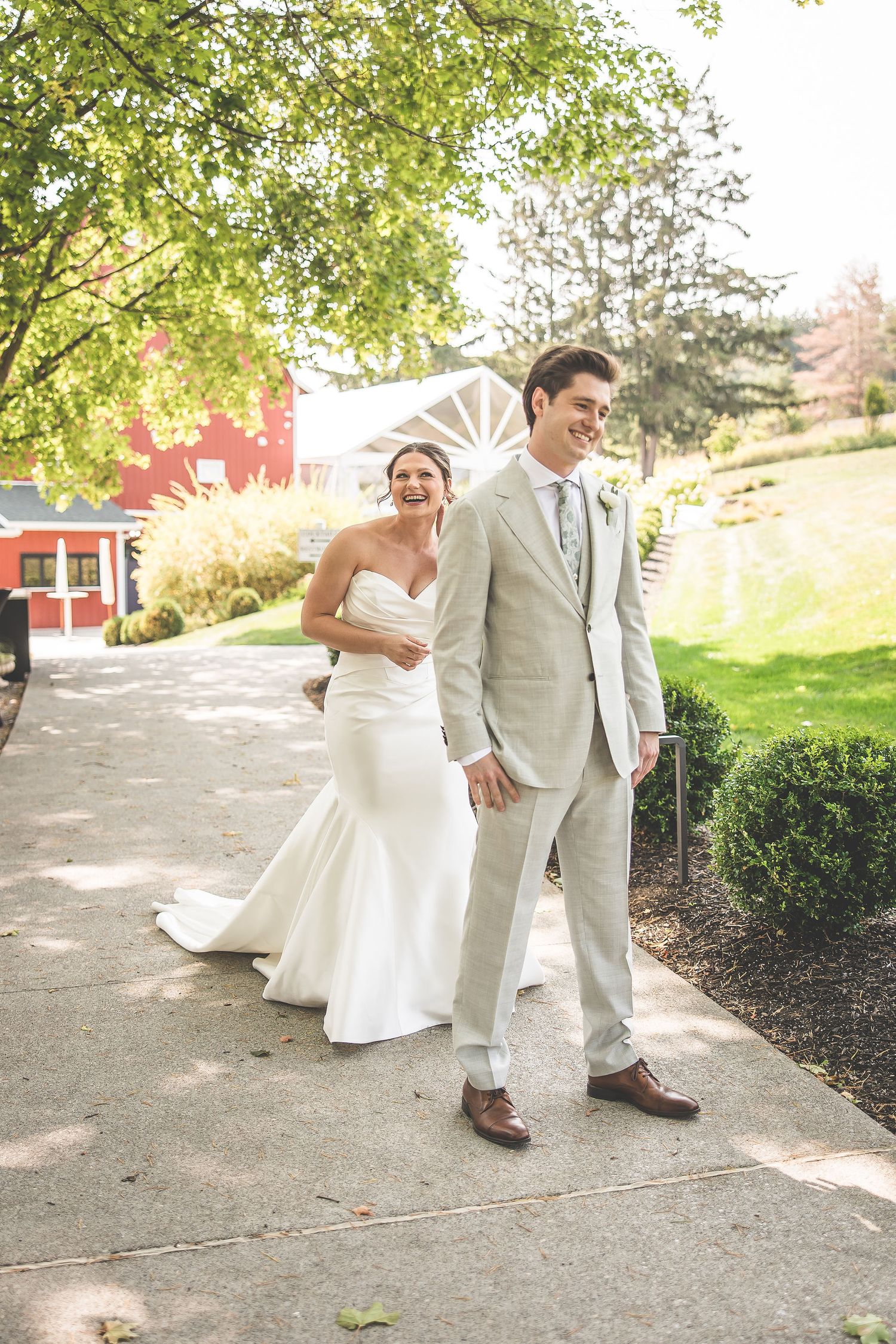 Couple shares joyful moments together on a garden path with a red barn in the background.