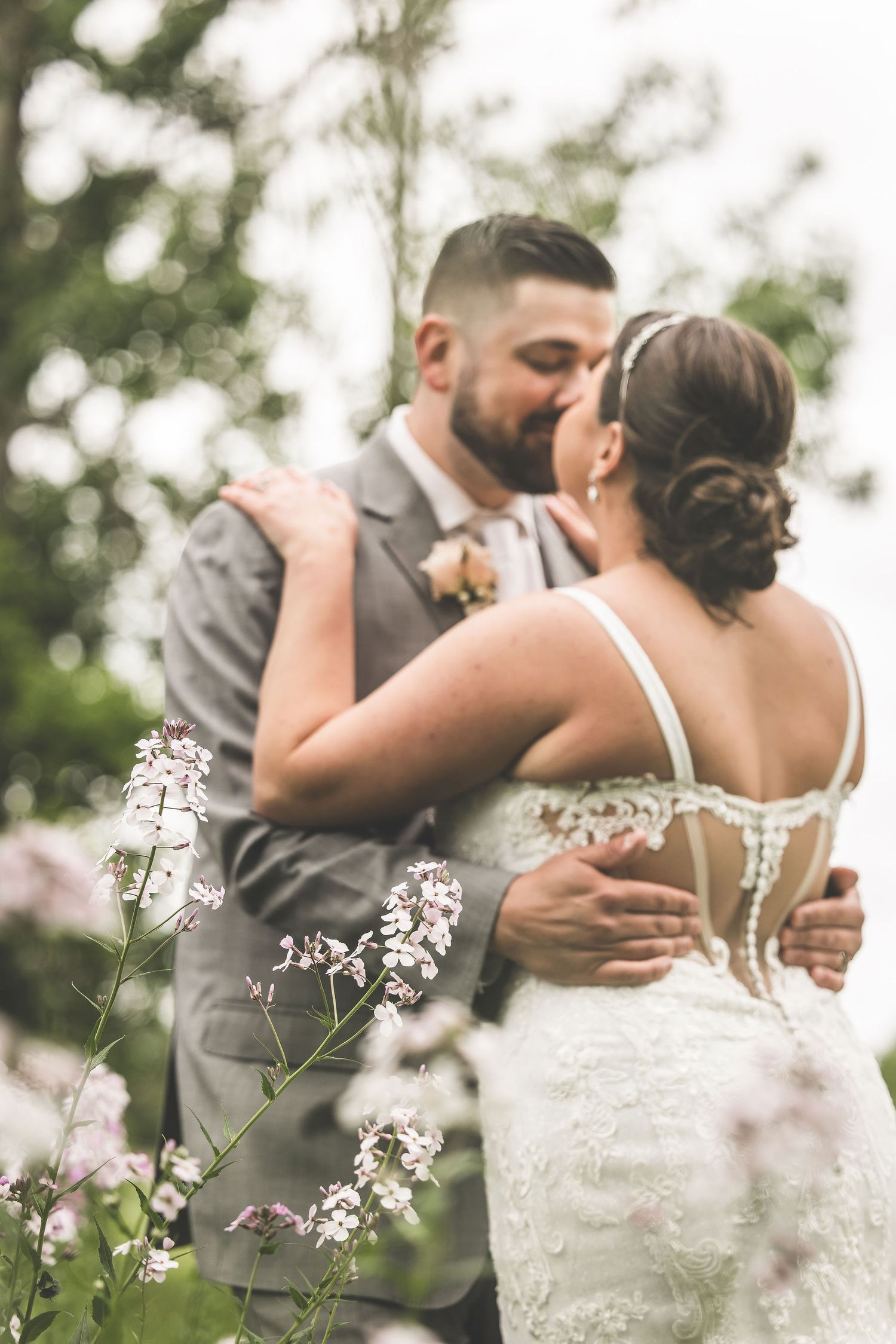 An intimate wedding portrait showing a tender embrace among delicate white wildflowers.