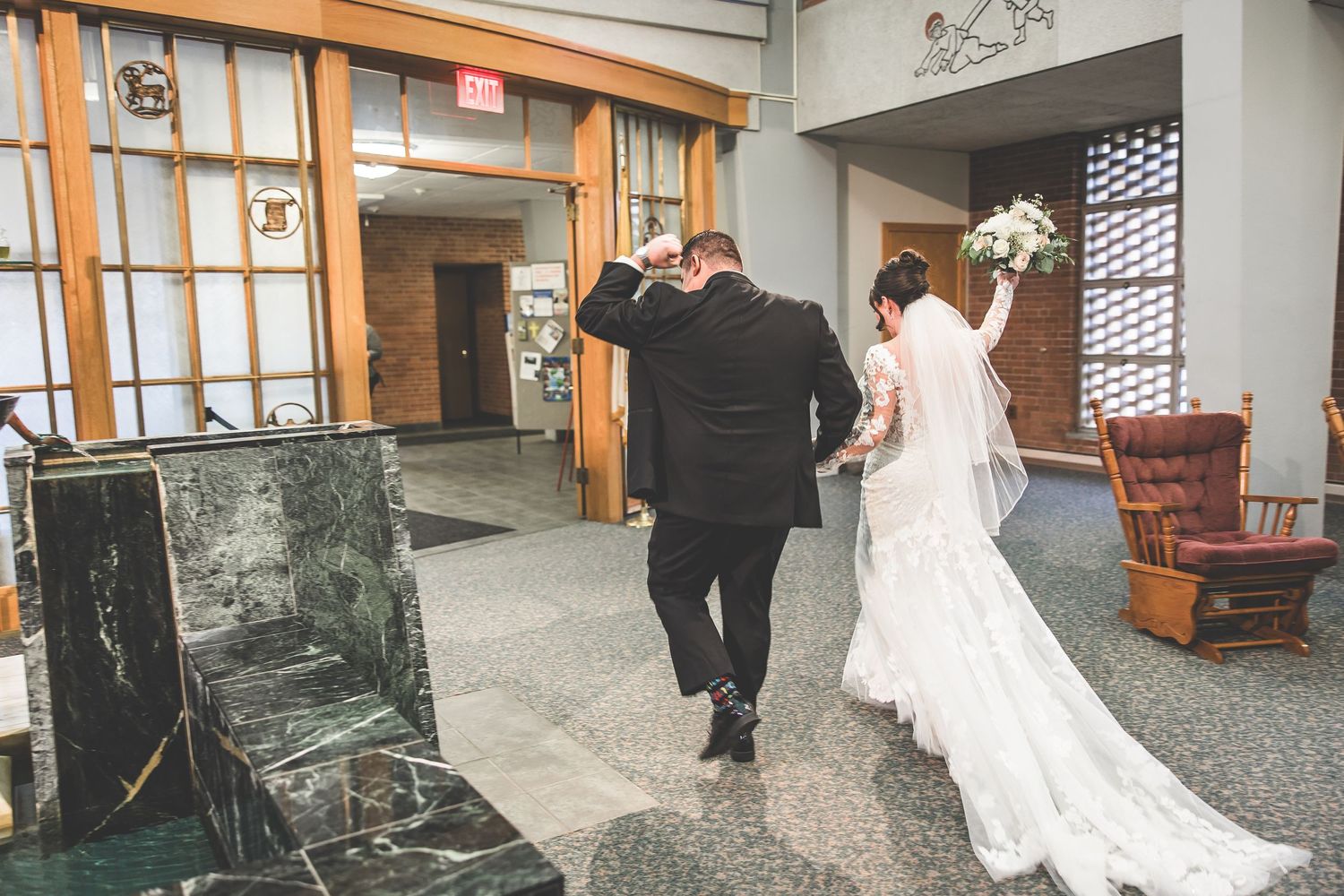 Wedding party walking through modern church hallway with wooden accents.