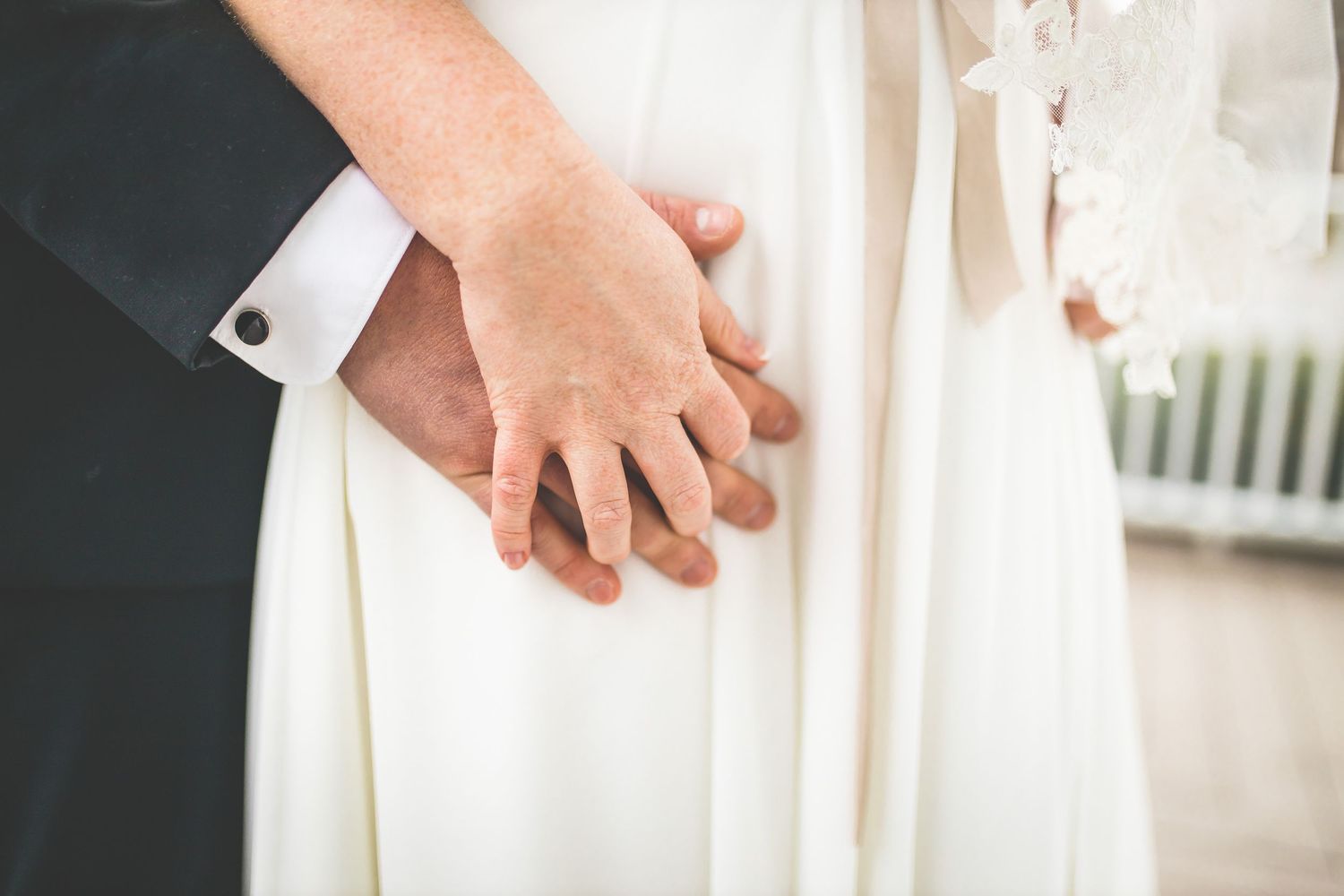 Elegant wedding couple walking on a white porch with columns in classic formal attire.