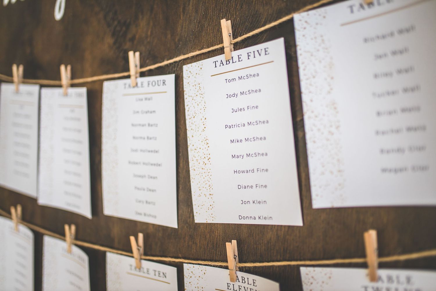 Wedding seating chart with name cards hung on string with wooden clothespins.