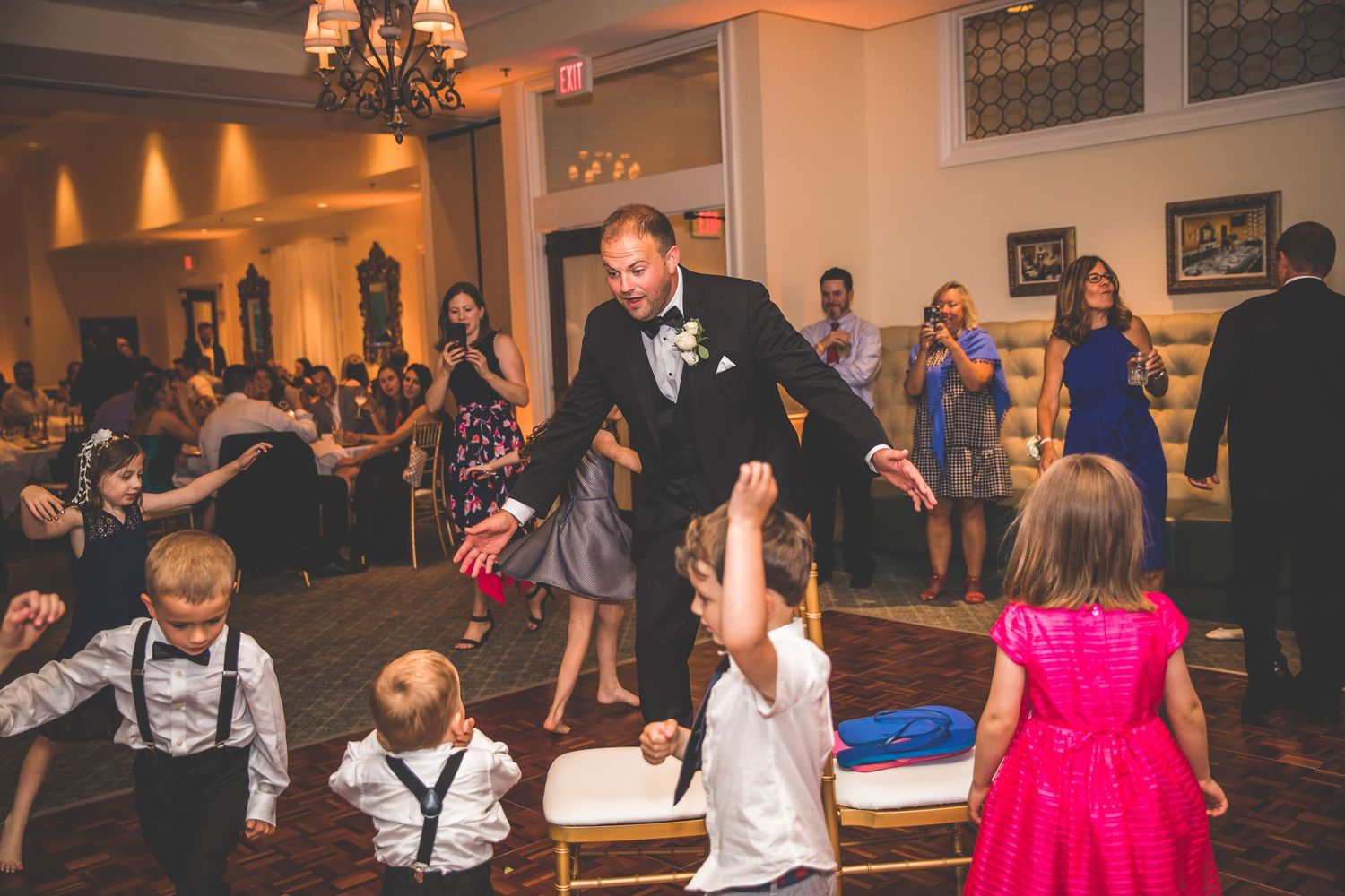 Wedding reception dance floor filled with guests celebrating under warm lighting.
