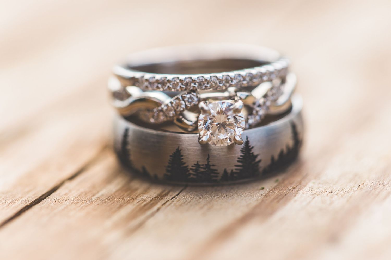 Close-up of wedding rings with intricate designs on wooden surface.