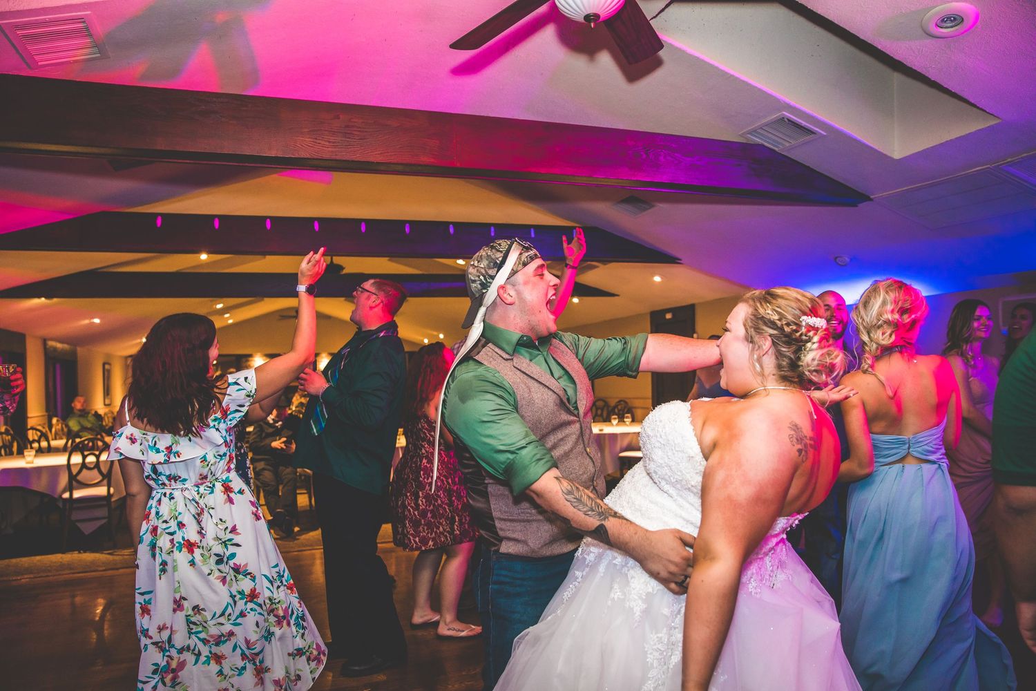 Wedding reception dance party with colorful lighting and guests celebrating on the dance floor.