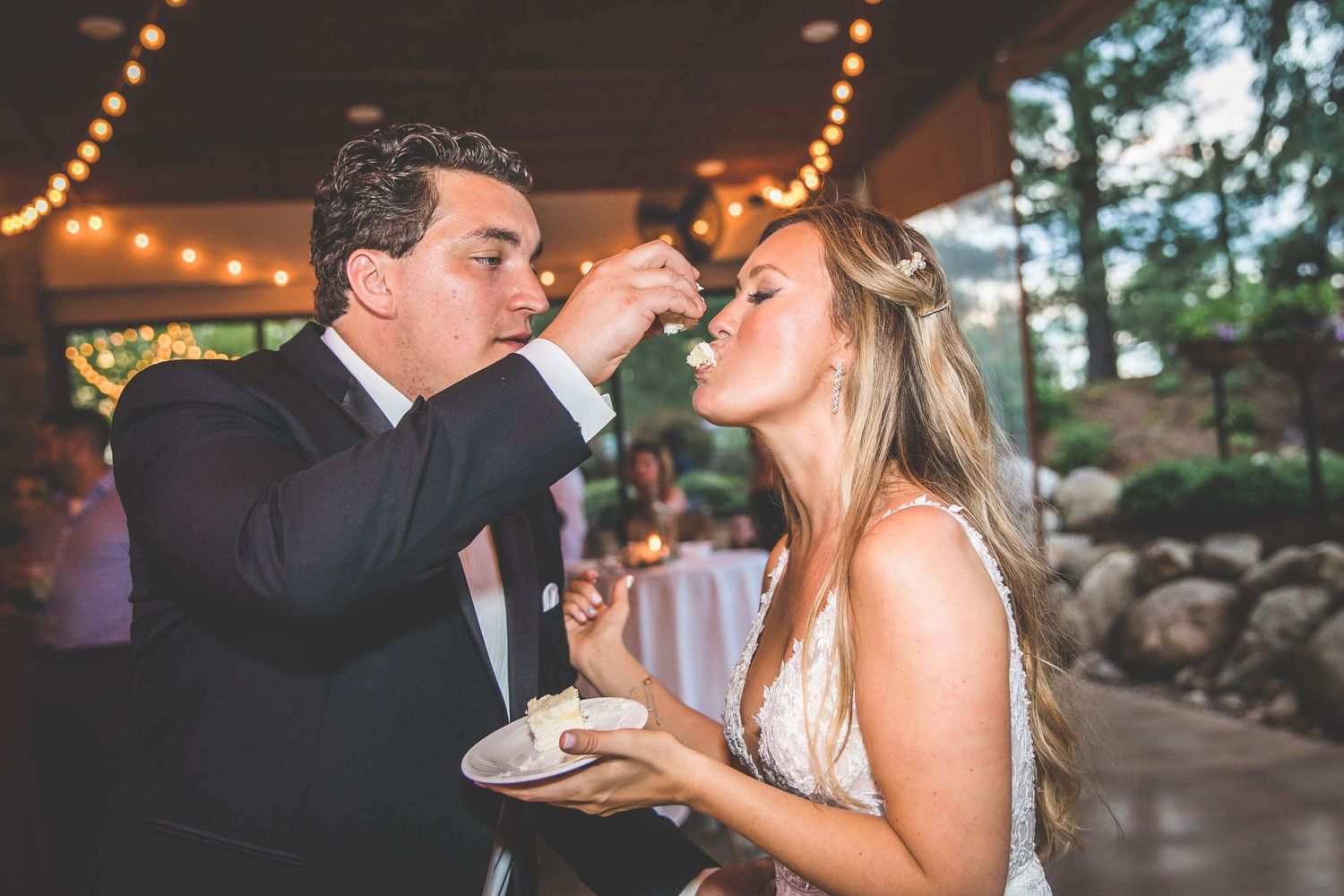 Couples slow dancing at an elegant wedding reception with string lights overhead.