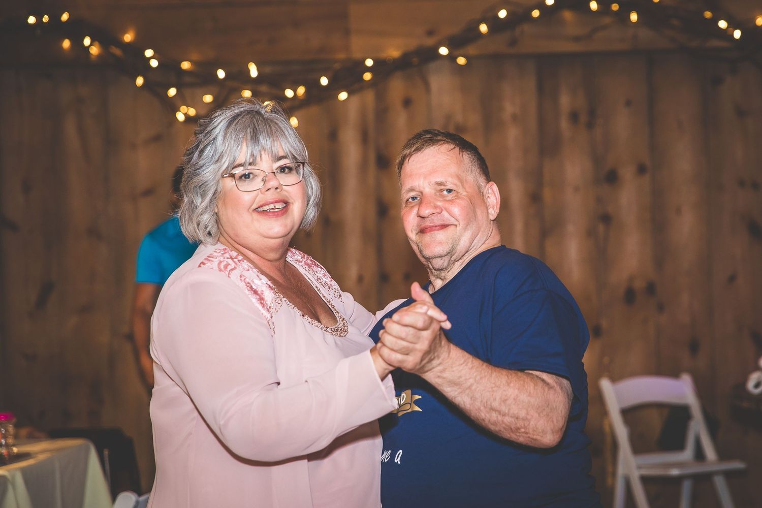 Wedding celebration in a rustic barn venue with string lights creating a warm atmosphere.