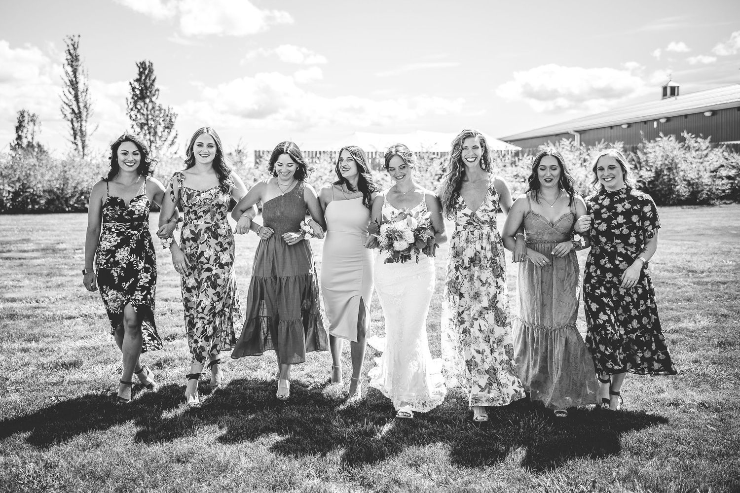 Bridal party poses outdoors against a scenic mountain backdrop on a sunny day.