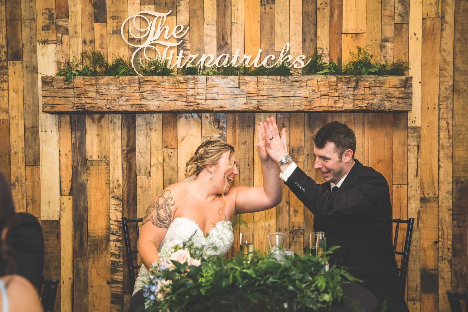 Rustic wooden wall backdrop with string lights at wedding reception venue.