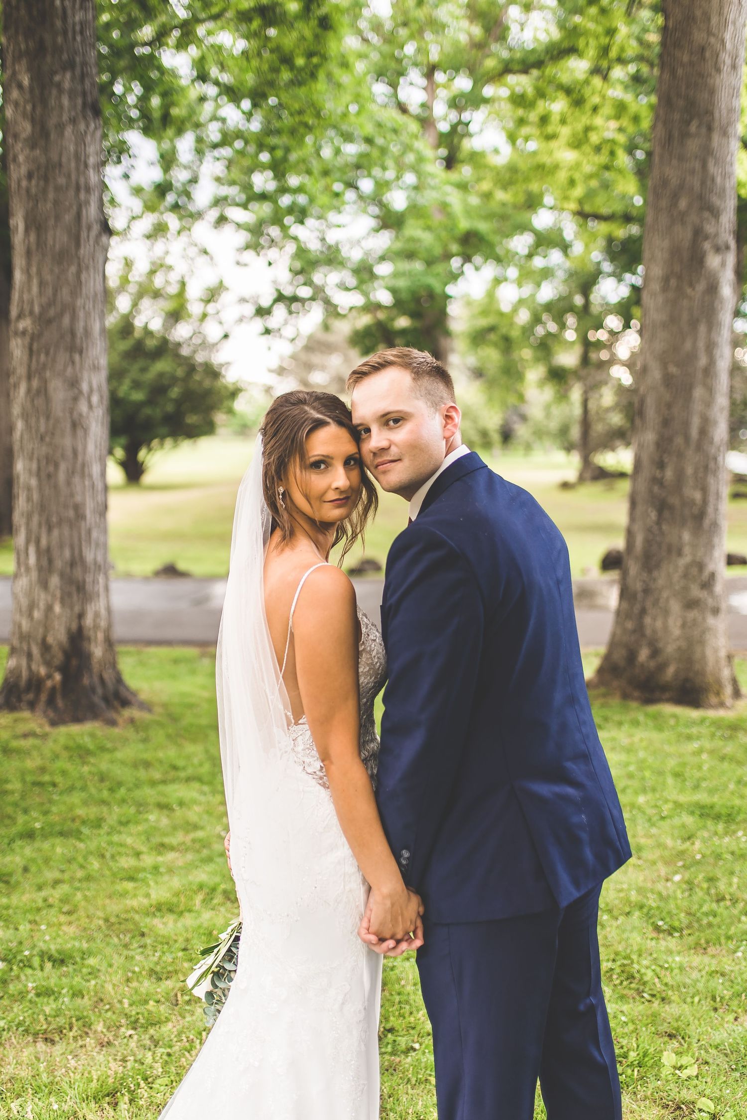 Candid wedding portraits captured in natural outdoor setting with tall trees.