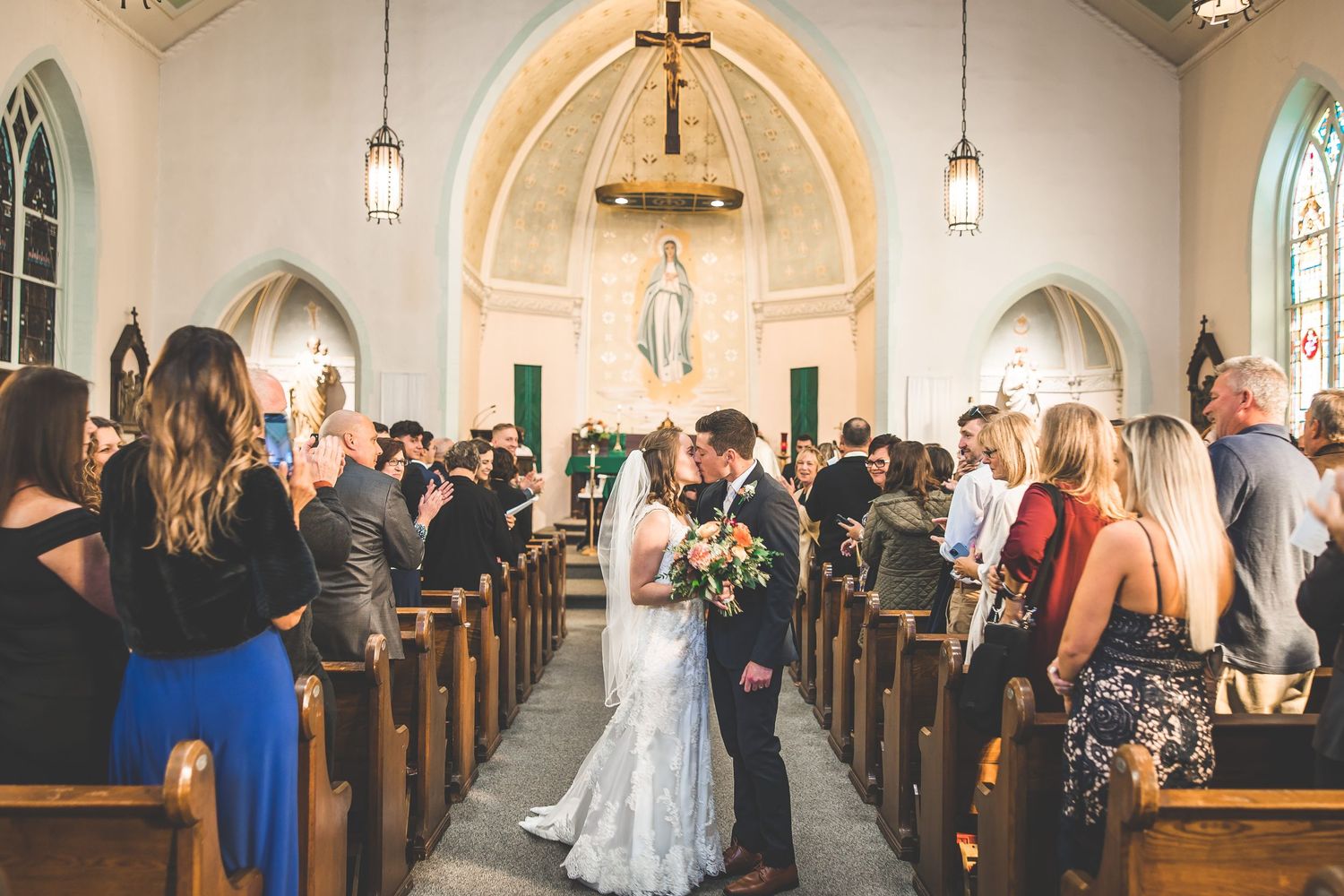 Panoramic view of a church sanctuary filled with wedding guests and decorative lighting.