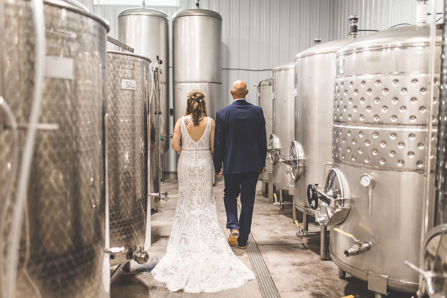 Panoramic view of a winery cellar with stainless steel tanks and wedding couple.