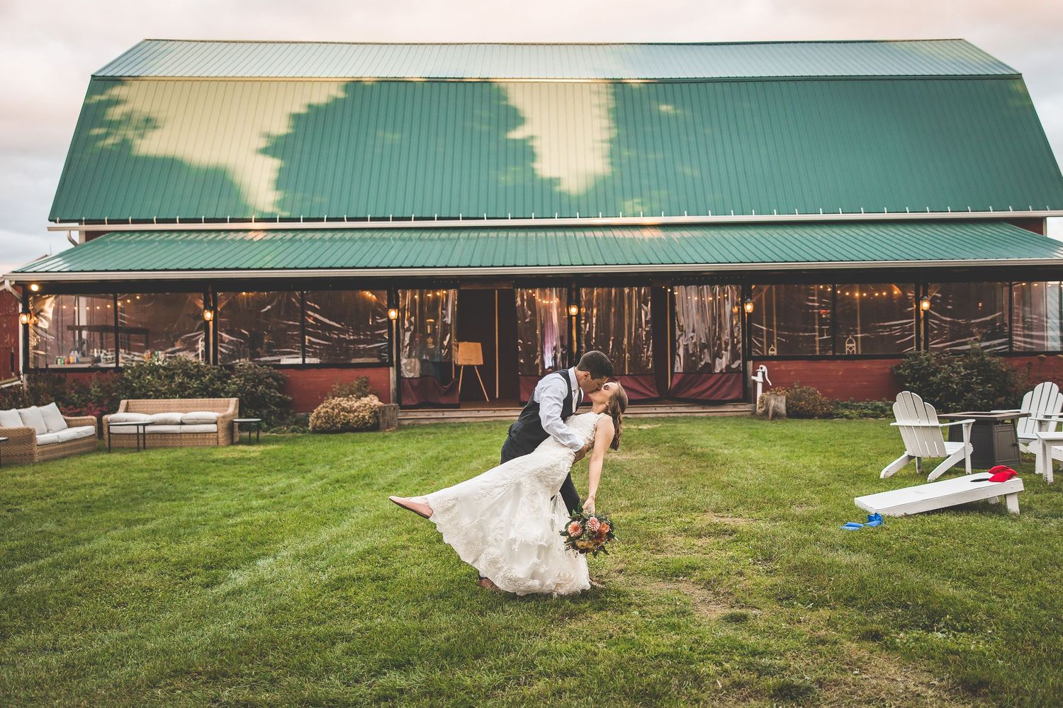 Rustic barn wedding venue with green lawn and white decorations in an outdoor setting.