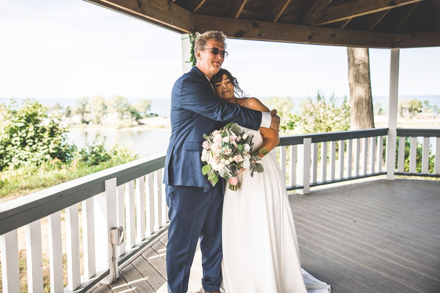 Wedding couple embraces during first look photos on covered outdoor deck.