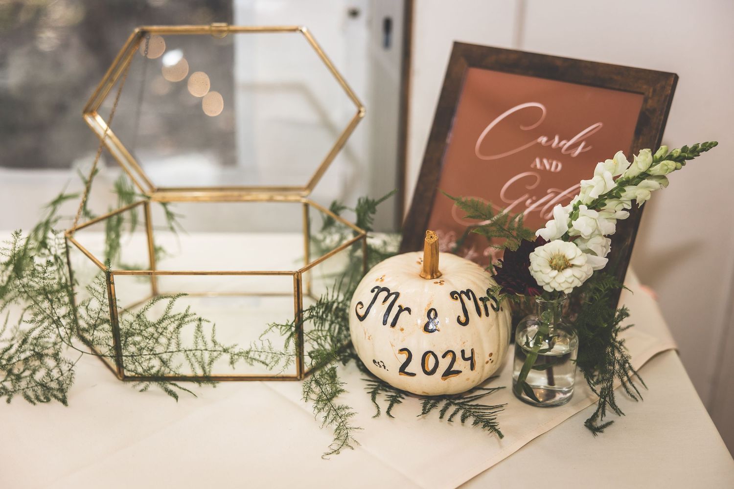 Wedding decor features geometric gold frames with greenery and 2024 signage.