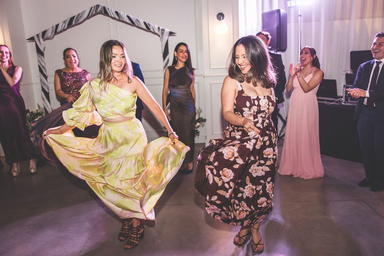 Wedding celebration with dancers twirling in formal attire under purple mood lighting.