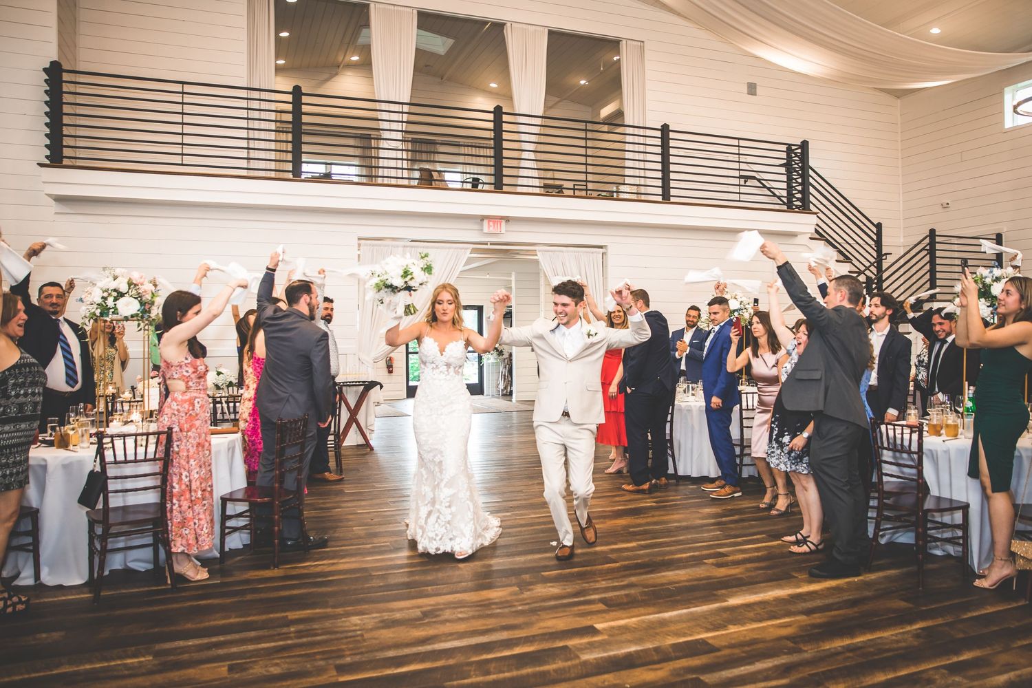 Wide shot of indoor wedding reception with guests mingling and dancing.