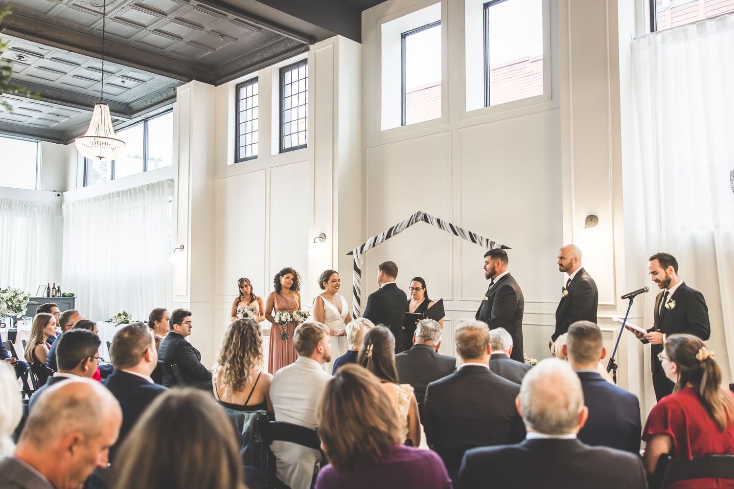 Modern wedding ceremony space with industrial windows and elegant white wall paneling.