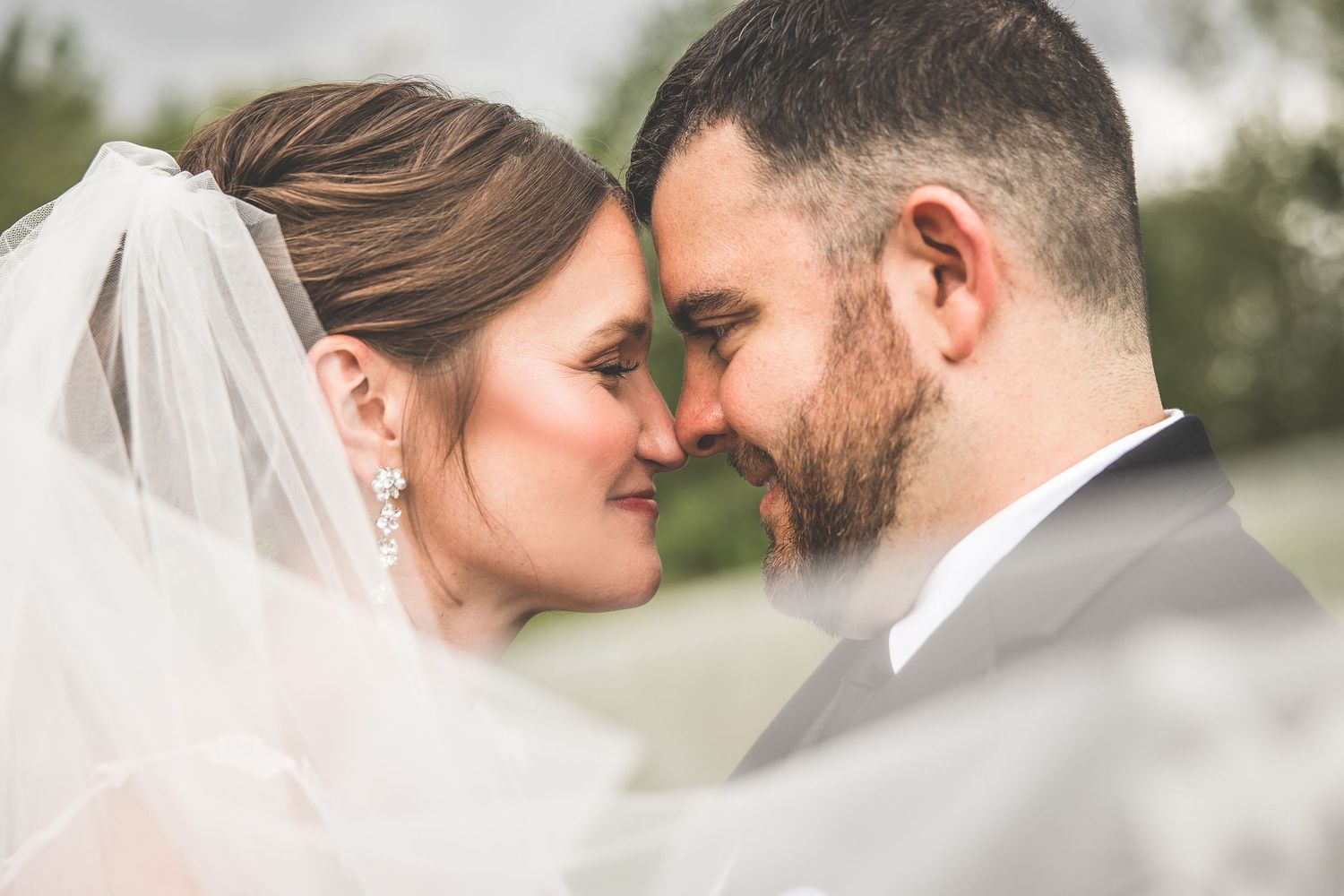 Close-up wedding portrait showing a tender moment between newlyweds with delicate veil details.