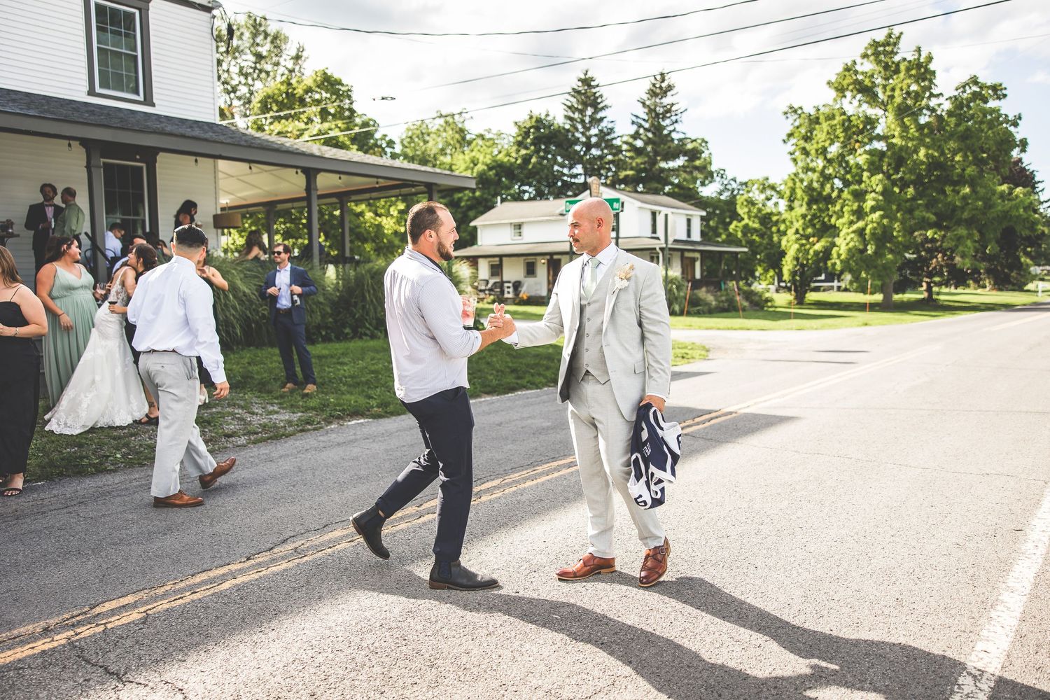Wedding guests walking along a paved road during an outdoor celebration.