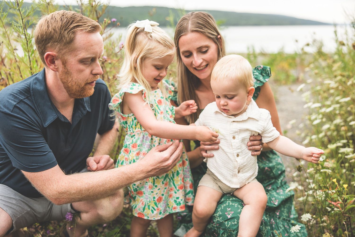 Family sharing tender moments together in a natural outdoor setting near the water.