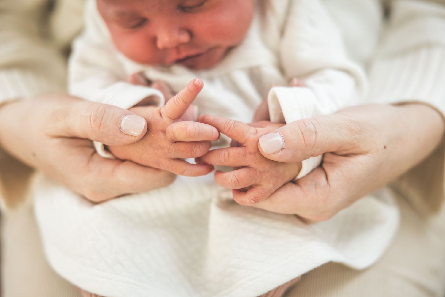 Close-up shots of gentle hands cradling a sleeping newborn baby.