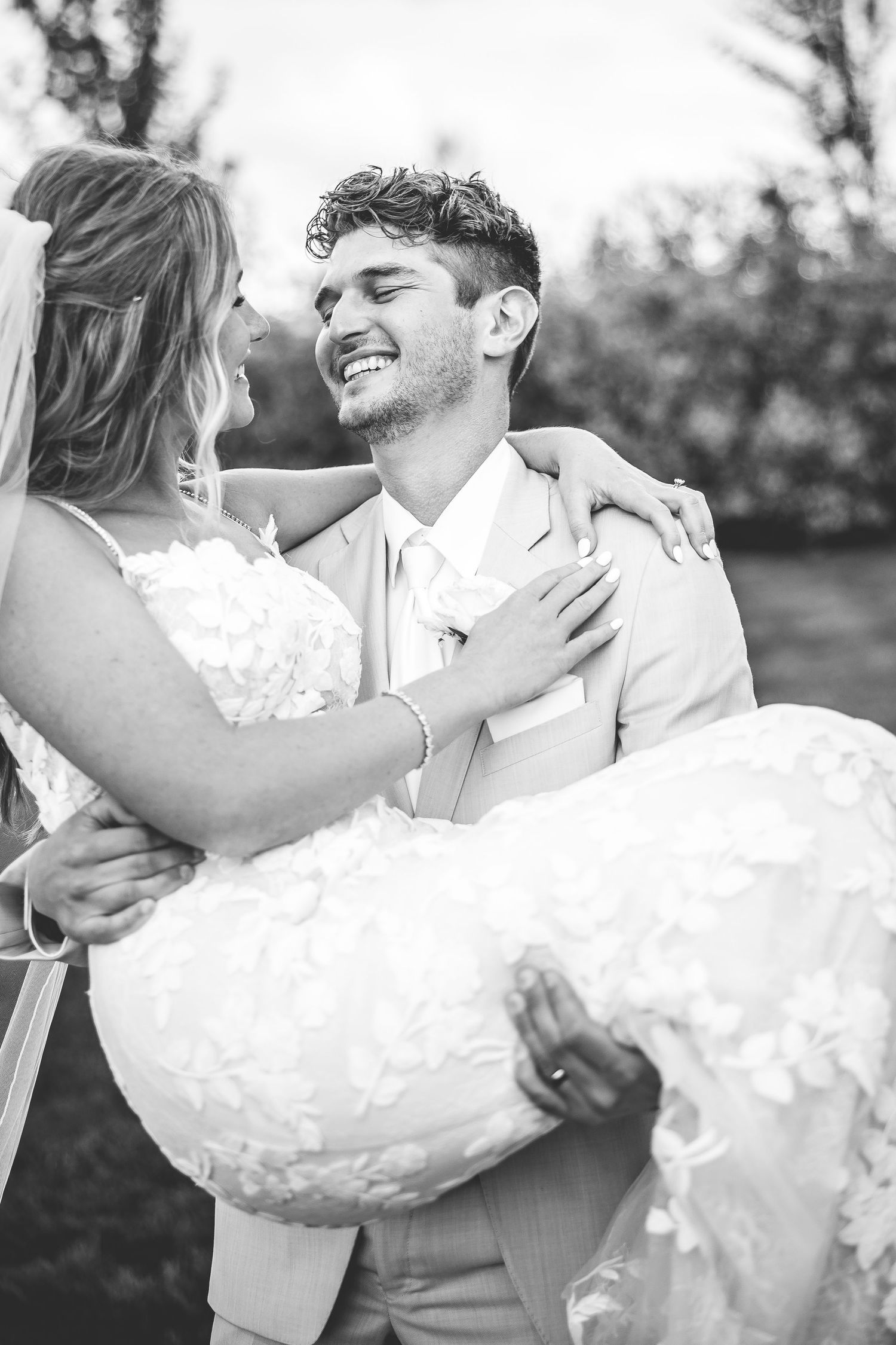 Black and white wedding portraits capturing joyful moments between newlyweds outdoors.