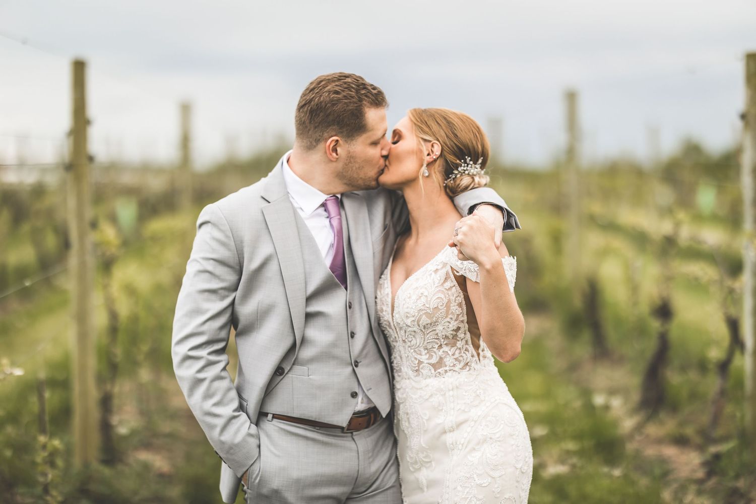 Newlyweds share a tender moment among vineyard rows on their wedding day.