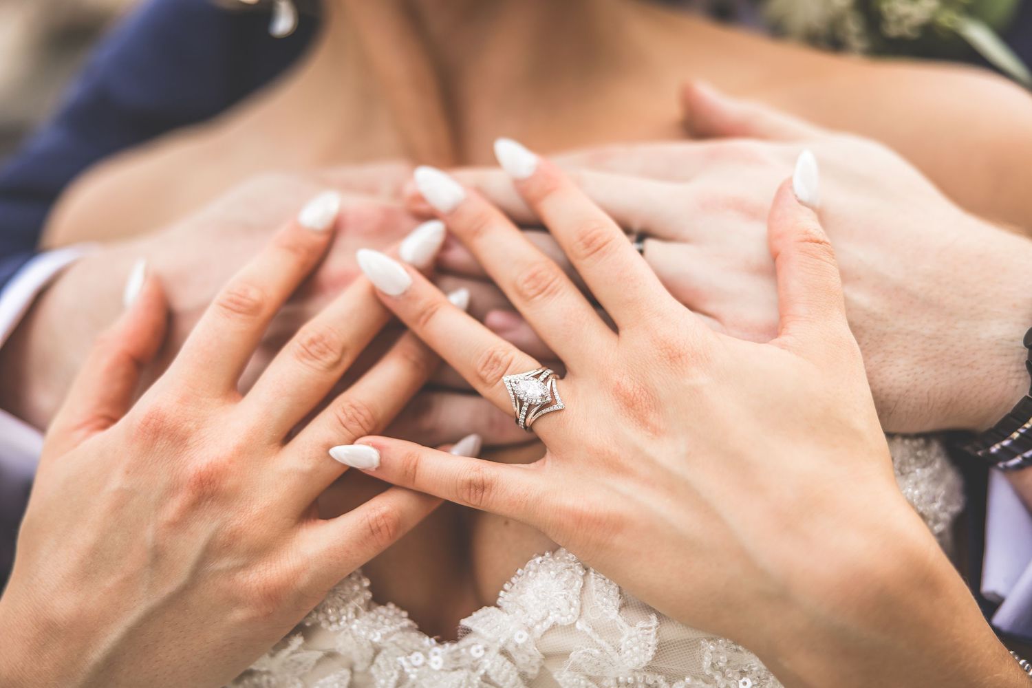 Close-up of hands showing wedding rings with delicate lace details in the background.