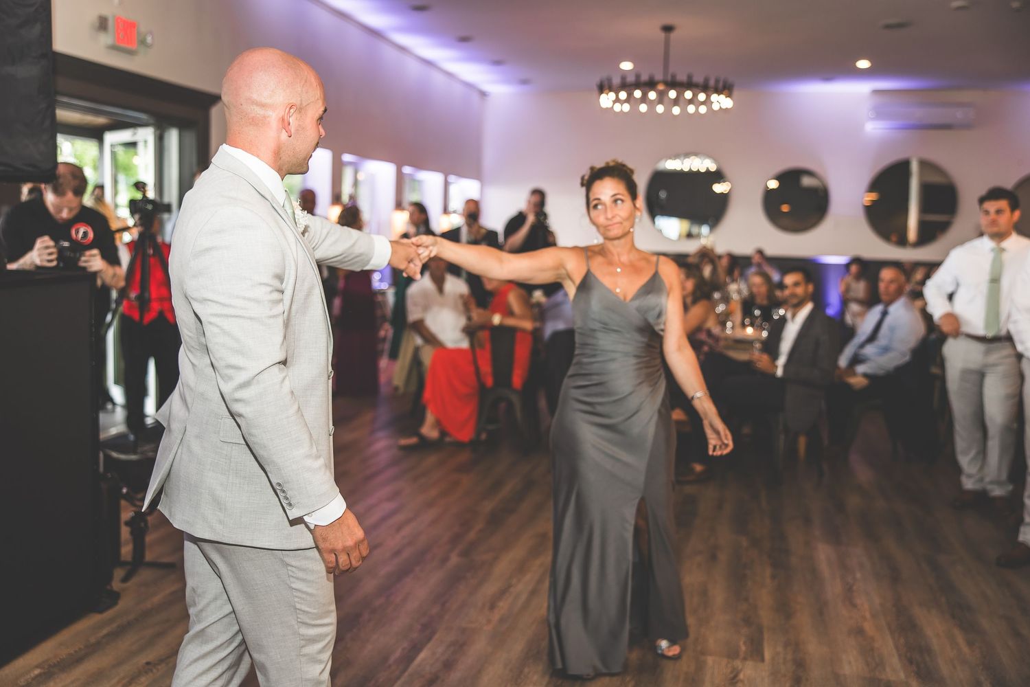 Large wedding reception venue with purple uplighting and hardwood floors.