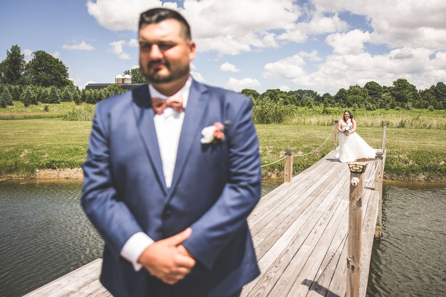 Wedding couple poses on a wooden dock by a lake on their special day.