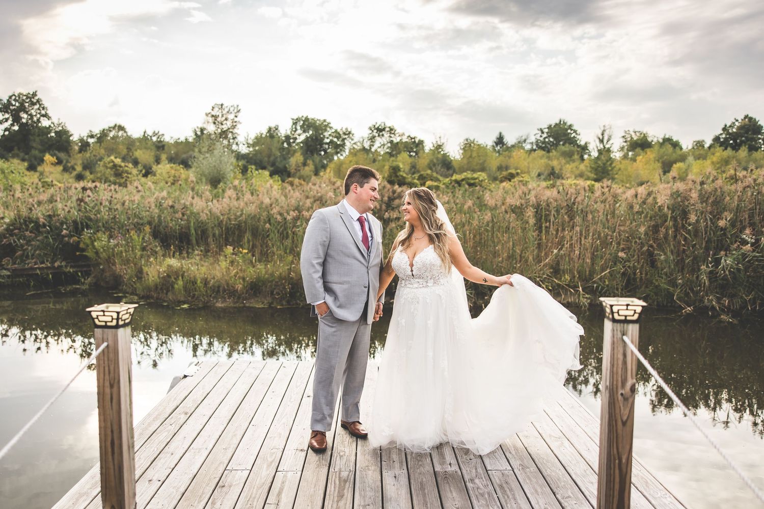 Romantic wedding photos on wooden dock overlooking serene lake at sunset.