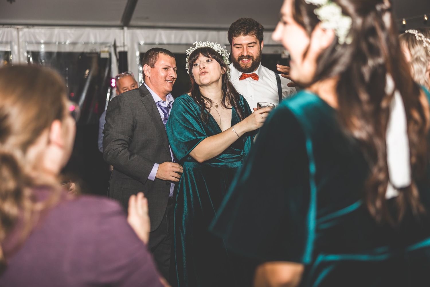 Wedding reception dance party with guests celebrating under ambient lighting.