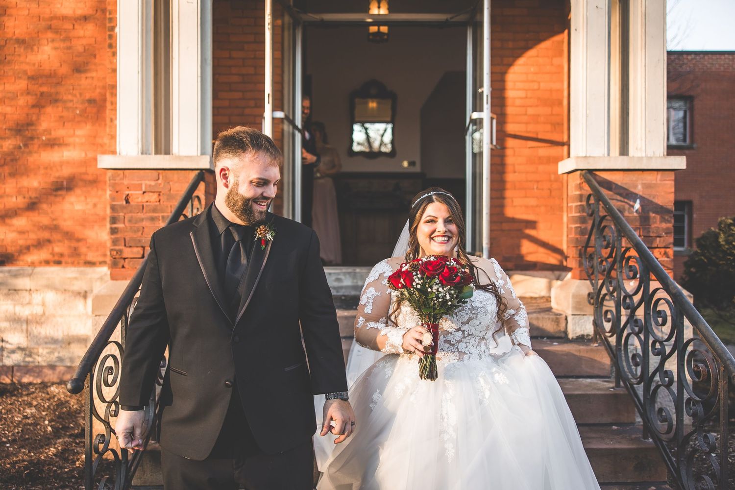 Wedding party posing outside a red brick church building on a sunny day.
